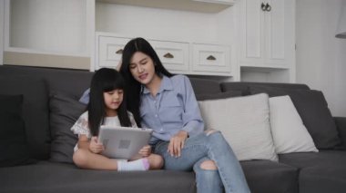 Family concept of 4k Resolution. Asian mother and daughter playing tablet in living room.