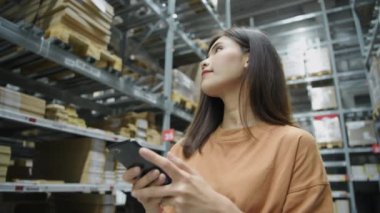 Shopping concept of 4k Resolution. Asian female customer checking price by mobile phone in warehouse.