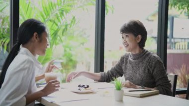 4k Kararlılığın iş konsepti. Asyalı iş adamları bir kahve dükkanında toplantı yapıyorlar. Kafe personeli servisi..