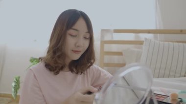 4k Çözünürlük 'ün güzellik konsepti. Asyalı kızlar yatak odasındaki yatakta makyaj yaparlar..