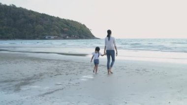Holiday concept of 4k Resolution. Asian mother and daughter walking by the sea. summer vacation travel.