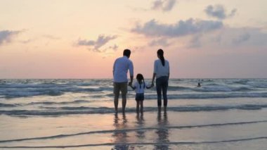 Tatil konsepti 4k Çözünürlük. Asyalı ebeveynler ve kızlar sahilde eğleniyorlar. Yaz tatili.