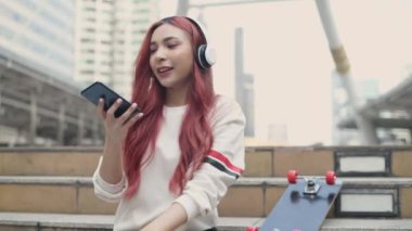 Tatil konsepti 4k Çözünürlük. Şehirde müzik dinleyen Asyalı kadınlar. Genç kız modası.