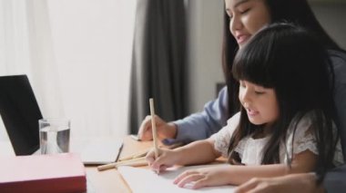 Aile kavramı 4k Kararlılığı. Asyalı anne çalışıyor ve evde kızına bakıyor..