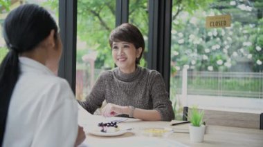 4k Kararlılığın iş konsepti. Asyalı iş adamları bir kahve dükkanında toplantı yapıyorlar. Kafe personeli servisi..