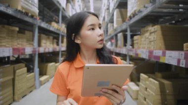 4k Kararlılığın iş konsepti. Asyalı bir kadın depoda modern teknolojiyle ürünleri kontrol ediyor..