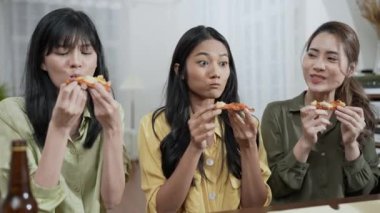 Tatil konsepti 4k Çözünürlük. Bir grup Asyalı bayan arkadaş evde birlikte pizza yiyorlar. Eğlenceli ve heyecan verici eğlence aktiviteleri.