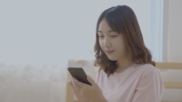 4K解像度の休日の概念 アジアの女の子はベッドルームで携帯電話を再生 — ストック動画