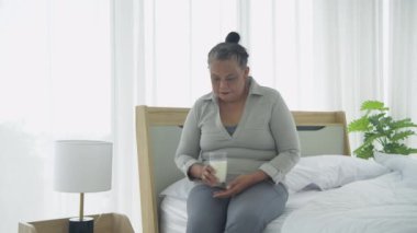 Sağlık konsepti 4k Çözünürlük. Evde süt içen Asyalı yaşlı kadın..