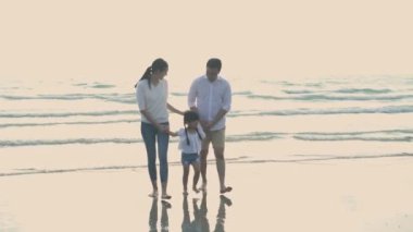 Tatil konsepti 4k Çözünürlük. Anne babalar sahilde yürümek için kızlarının elini tutuyorlar. Yaz tatili.