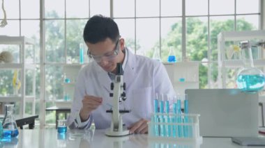 Araştırma konsepti 4K çözünürlüğü. Bir Asyalı test tüpüne sıvı damlatıyor..