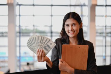 Elinde bir dolarlık banknot tutan Asyalı kadın. Para kazanacağından emin..