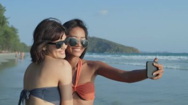 Tatil konsepti 4k Çözünürlük. Mayolu genç Asyalı kadınlar sahilde selfie çekiyorlar..