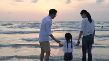 Tatil konsepti 4k Çözünürlük. Asyalı ebeveynler ve kızlar sahilde eğleniyorlar. Yaz tatili.