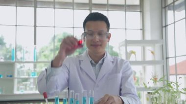 Araştırma konsepti 4K çözünürlüğü. Bir Asyalı test tüpüne sıvı damlatıyor..