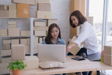 Ofisteki müşterilere ürün götürmeye hazırlanan Asyalı kadınlar. Bilgisayardan müşteri bilgilerini kontrol ediyor..