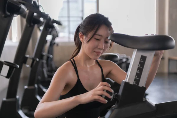 Asian woman preparing exercise equipment in the gym.
