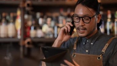 Night club concept of 4k Resolution. The bartender is taking orders from customers with the phone in the restaurant. A group of specialized clubs that sell alcoholic beverages.