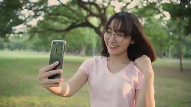 4Kの解像度の観光コンセプト 庭で携帯電話で遊んでいるアジアの女性 — ストック動画