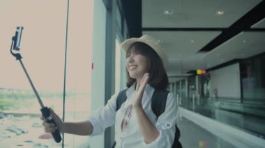 4k Kararlılığın Turizm konsepti. Asyalı kadın havaalanında selfie ya da video çekiyor..