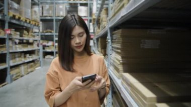 Shopping concept of 4k Resolution. Asian female customer checking price by mobile phone in warehouse.