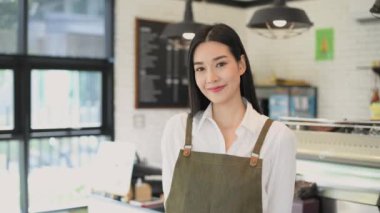 Kafe konsepti 4k Kararlılık. Asyalı bir kadın dükkanda güvenle kollarını kavuşturuyor..