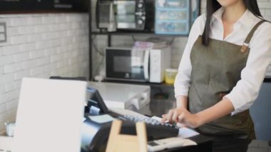 Kafe konsepti 4k Kararlılık. Asyalı bir kadın tezgahta parasını alıyor..