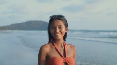 Tatil konsepti 4k Çözünürlük. Mayolu genç bir Asyalı kumsalda yürüyüş yapıyor..