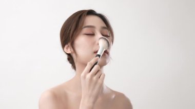 4k Çözünürlük 'ün güzellik konsepti. Asyalı kızlar yanaklarını pudra temeli ile fırçalıyorlar..