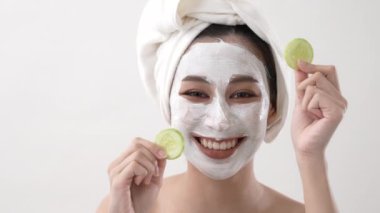 Beauty concept of 4k Resolution. Asian girl putting cucumber at her eyes on a white background.