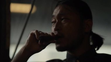 Gece kulübü konsepti 4k Kararlılık. Restoranda puro içen Asyalı bir adam. Alkollü içecekler satan bir grup özel kulüp..