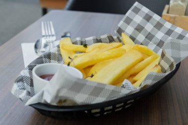 Lezzetli altın patates kızartmaları sosa batırmak için yanında ketçap olan şık bir sepette servis edilir..