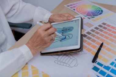 Parlak çalışma alanında renk paletleri ve çizimlerle tablet üzerinde dijital sanat yaratan bir tasarımcı.