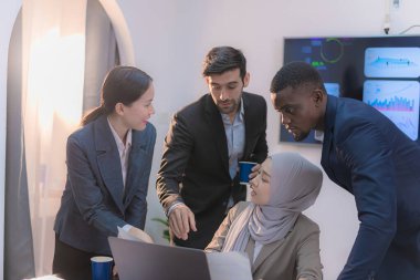 İş sunumları ve veri analizleri üzerinde strateji oluşturmak için modern bir ofiste işbirliği yapan çeşitli profesyoneller.