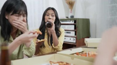 Tatil konsepti 4k Çözünürlük. Bir grup Asyalı bayan arkadaş evde birlikte pizza yiyorlar. Eğlenceli ve heyecan verici eğlence aktiviteleri.