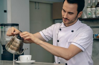 Yetenekli bir barista çaydanlıktan kahve fincanına sıcak su dökerek mükemmel bir demleme yapar..