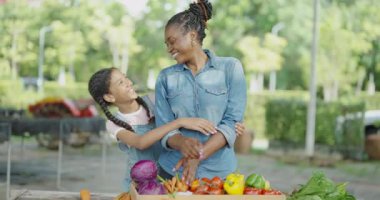 4K çözünürlüğünün tarım konsepti. Bir kız, annesinin markette sebzeleri sepete koymasına yardım ediyor..