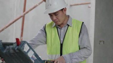 İnşaat konsepti 4K çözünürlük. Mühendis inşaat alanındaki kutudan aletleri alıyor..