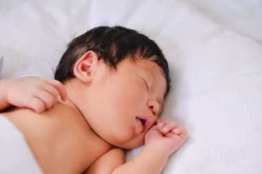 Huzurlu, yeni doğmuş bir bebek yumuşak bir battaniyenin üzerinde mışıl mışıl uyuyor. Huzurlu bir ortamda masumiyet ve sükuneti somutlaştırıyor..