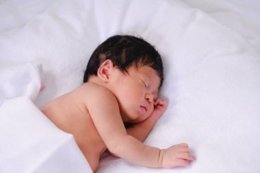 Huzurlu, yeni doğmuş bir bebek yumuşak bir battaniyenin üzerinde mışıl mışıl uyuyor, masumiyet ve sükuneti somutlaştırıyor..