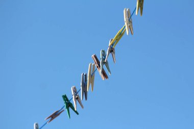 Rengarenk eski plastik antika mandallar, çeşitli soluk renk boyutları ve şekiller, açık mavi gökyüzü arka planında, tek bir açık mavi ipin üzerine yoğun bir şekilde yerleştirilir.