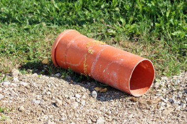 Turuncu PVC büyük çaplı inşaat borusunun bir kısmı sarı poliüretan köpükle kaplı ya da yerel inşaat alanının çakıl yolunun kenarına bırakılmış köpük köpüklü sıcak bahar gününde kesilmemiş çimlerin yanına.