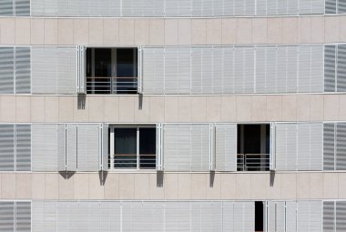 Açık ve kapalı beyaz metal pencereler güneşli bahar günlerinde güneşli büyük şehir binasının güneşli tarafındaki balkonları kaplıyor.