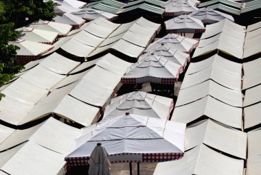 Geleneksel gri ve beyaz Avrupa pazarı şemsiyelerinin en üst görüntüsü sıcak bahar günlerinde yerel organik bakkaliye satan satıcıların üzerindeki şemsiyeleri gölgeliyor