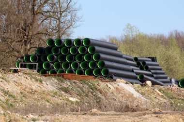 İçi canlı yeşil borularla dolu büyük siyah kıvrımlı plastik borular, drenaj veya kamu hizmetleri altyapı projelerine yerleştirilmeye hazır bir set üzerine düzgünce düzenlenmiştir.