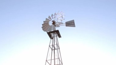 Güney Afrika galvanize çelik çiftlik yel değirmeni mavi gökyüzü arka planıyla rüzgarda dönüyor