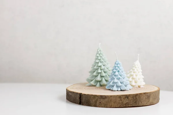 Handmade decorative candles made of natural soy wax in the form of a Christmas tree in blue, green and white colors on a wooden stand. High quality photo