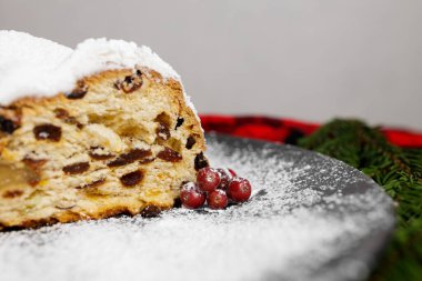 Kırmızı ve siyah masa örtüsü, kozalak, böğürtlen, Noel ağacı dalları ile süslenmiş siyah bir tabakta kesilmiş bir Alman Noel ağacı parçası. Yüksek kalite fotoğraf