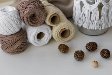 Örgü, koni, ahşap boncuklar ve masanın üstündeki makrome tekniğine takılı kavanoz için taşaklardan oluşan bir kompozisyon..