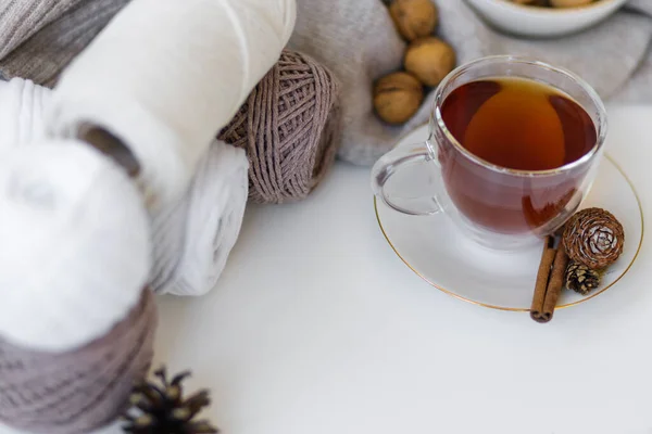 stock image  Cozy Christmas composition. Transparent cup of black tea on saucer on table with cinnamon and cones. Decorated with a gray sweater, nuts and balls for knitting. High quality photo